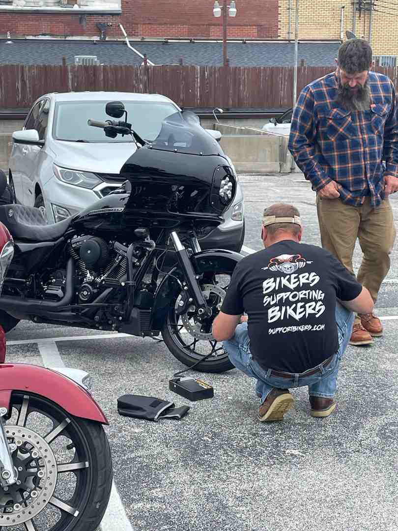 rider inspecting motorcycle tire and brake - motorcycle maintenance 101