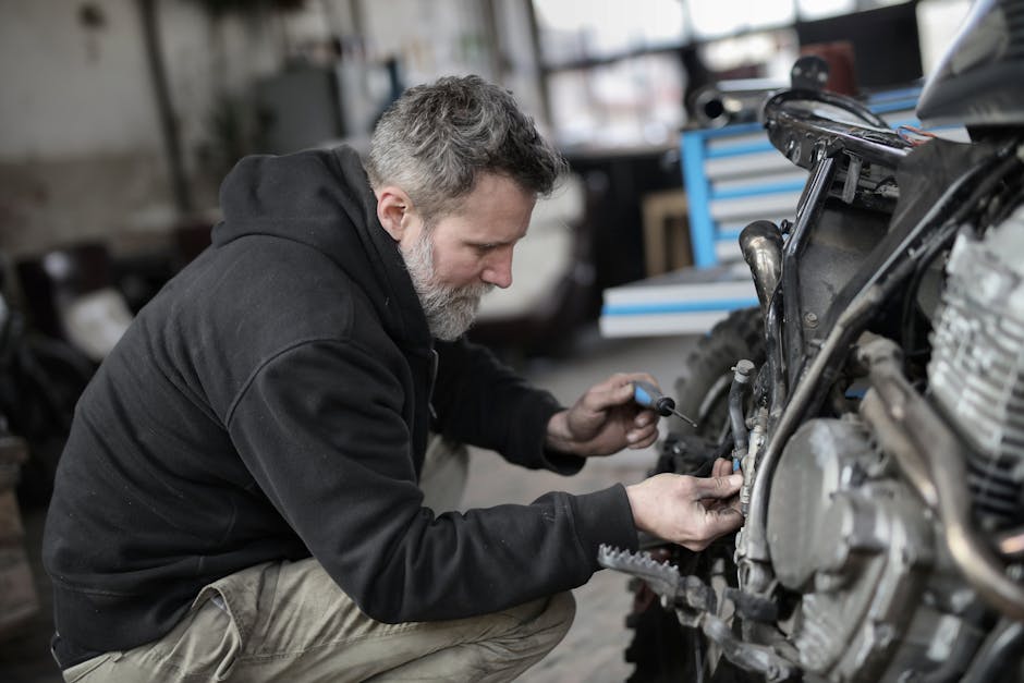 Motorcycle mechanic working on an engine - Motorcycle repair shops