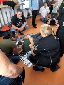 Sonny The Badger and individuals standing over a person on the ground learning how to save a life- accident scene management training